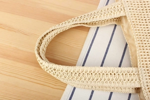 Close-up of woven shoulder bag showing fine straw texture and fabric lining detail