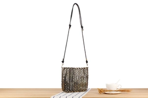 Close-up of metallic woven shoulder bag featuring gold, silver, and black sequins texture