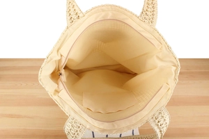 Internal view of the woven tote bag showing the zipper pocket and beige lining detail