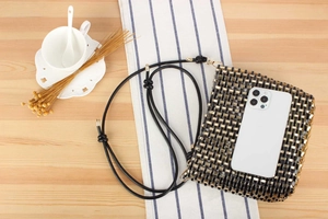 Detail of hand-woven black and gold beaded mini bag showing daily phone capacity
