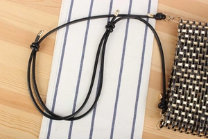 Close-up of black and gold woven texture with decorative knot on leather strap