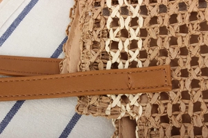 Detailansicht der Strohtasche mit weißer Kreuzwebung und braunem Leder-Schultergurt