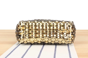 Close-up of gold and black woven handbag texture with metallic reflective surface