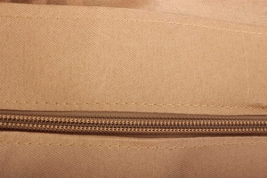Nahaufnahme der braunen gewebten Stoffstruktur und des robusten Reißverschlusses der Tasche
