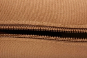 Detailaufnahme des braunen gewebten Canvas-Stoffs und des robusten Reißverschlusses