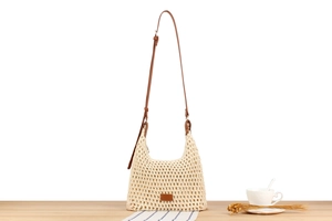 Detail of hollow crochet woven shoulder bag with adjustable brown faux leather strap