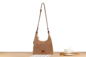 Detail of hand-woven straw bag with leather strap on a rustic table with coffee decor