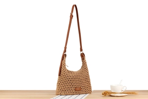 Detail of hand-woven hobo bag featuring adjustable brown leather strap and metal buckle
