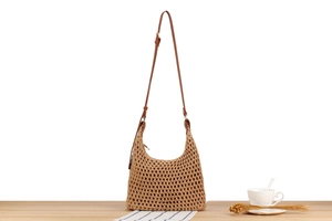 Detail of hollow woven texture and brown leather strap on hobo shoulder bag