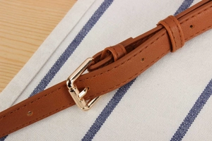 Close-up of brown leather strap with golden metal buckle and refined edge stitching