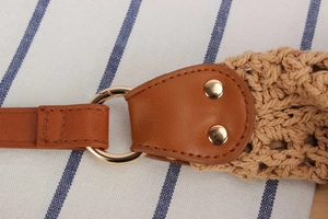 Detail of woven straw texture with brown faux leather and golden metal rings for women