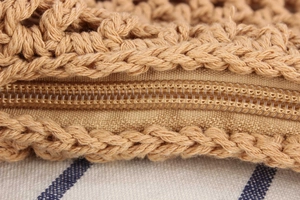 Macro detail of natural woven bag showing the zipper closure and fine texture