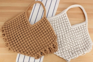 Detail of handmade hollow mesh weave tote bags with tassels in khaki and cream white