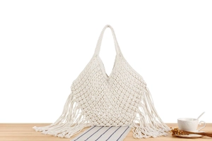 Detail of handmade macramé woven bag with tassels on a lifestyle background