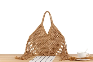 Detail of hand-woven mesh tote bag with tassels and natural bohemian styling