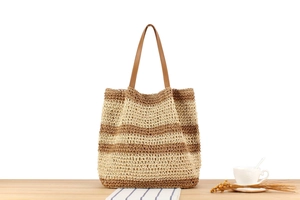 Close-up of beige and brown striped woven tote bag texture with leather handle details