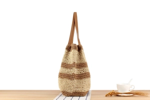 Detail of hand-woven straw tote bag with striped texture and premium leather handles
