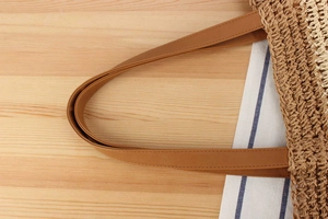 Close-up of woven tote bag featuring brown leather handles and artisanal hollow stitching