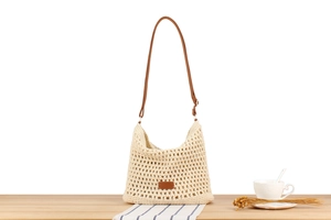 Detail of beige woven tote bag with brown leather patch on a lifestyle tabletop setting