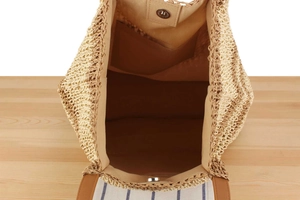 Detail view of woven straw bag interior with light brown lining and magnetic metal clasp