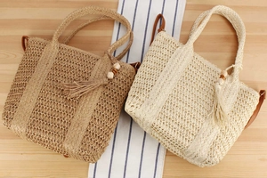 Close-up of beige and brown woven bags with fringe and wooden bead charms on table
