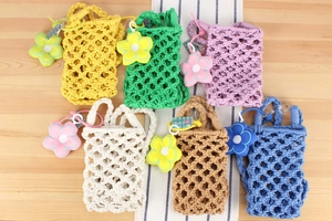Flat lay of colorful hand-woven cotton rope phone bags with plush sunflower charms