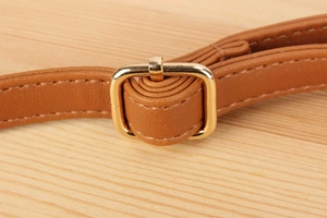Macro view of brown leather strap with polished gold buckle and precise stitching details