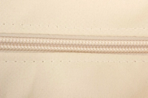 Detail showing smooth invisible zipper and refined stitching on beige woven bag fabric