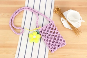 Detail of purple hand-woven cotton phone bag with textured mesh and yellow flower charm