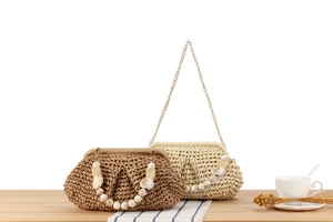 Dettaglio di pochette in paglia intrecciata marrone e beige con catene in marmo