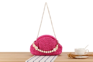 Close-up of rose red crochet woven bag with gold chain strap and marble beads detail
