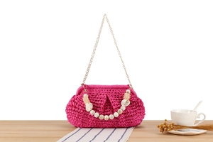 Dettaglio borsa intrecciata rosa con manico in perle di marmo e catena in oro chiaro