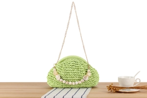 Close-up of light green woven cloud bag with gold chain and marble texture beads