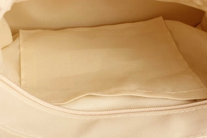 Detail view of woven bag cream canvas lining with organized pocket and sturdy zipper