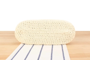 Detailed macro view of the oval woven base and cotton texture of this beige handbag