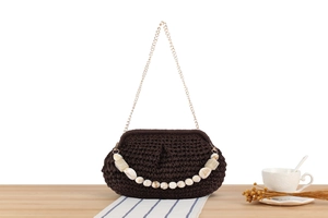 Dettaglio della pochette intrecciata marrone scuro con perline di marmo e tracolla a catena