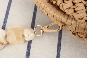 Close-up of woven bag texture with gold lobster clasp and marble pattern acrylic strap