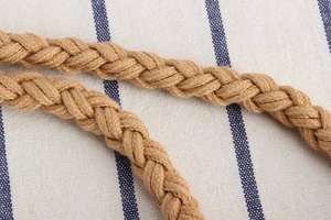 Detailed macro view of woven jute cotton rope with thick texture on striped fabric