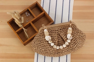 Detailed texture of woven straw bag with marble resin chain handle and gold hardware
