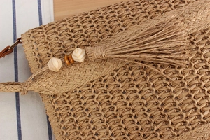 Detailed macro view of woven straw texture with decorative wooden beads and fringe tassels