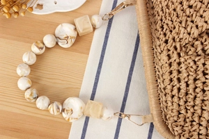 Detail of amber resin beads on woven bag strap with golden metal clasps and straw texture