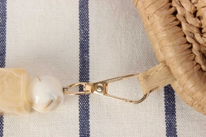 Detail of straw woven bag showing gold lobster clasp and decorative marble beads