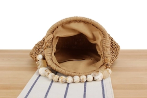 Close-up of woven straw bag showing interior lining and marble resin bead handle detail