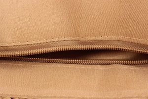 Close-up of the smooth zipper stitching and canvas texture on this khaki woven tote bag