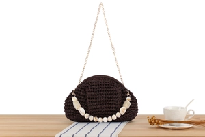 Detailed shot of dark brown crochet handbag with marble bead handle and gold chain strap