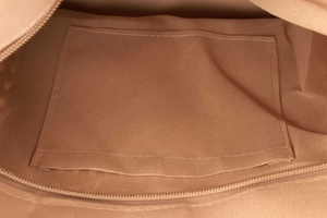 Internal view of tan woven bag showing canvas lining, inner pocket and zipper detail