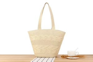 Close-up of cream woven tote bag with wavy patterns on a minimalist wooden table