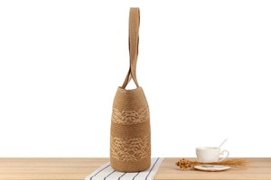 Close-up of a woven straw bucket bag with texture on a wooden desk with a coffee cup