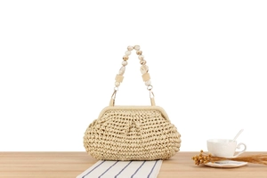 Detail of hand-woven beige straw bag featuring a unique marbled bead and resin handle