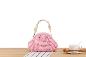 Detail of pink woven handbag featuring vintage marbled acrylic beaded handle on wood surface